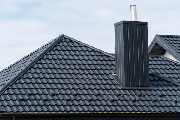House roof top covered with black metallic shingles. Beautiful modern roof of the house.