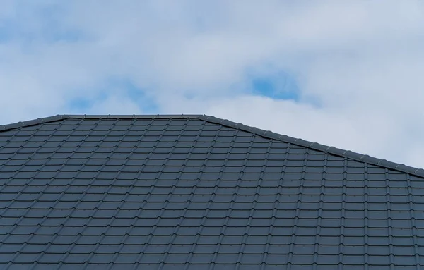 Black metal tile on the roof of the house. The material for the roof.