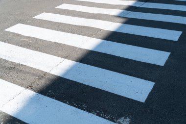 Yaya geçidi. Yaya geçidinin yeni beyaz çizgileri. Bir asfalt yolda yaya geçidi üzerindeki işaretlerin uygulaması.
