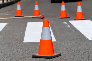 Yol onarımı, ön planda koni. Trafik konisi. Yeni yol işaretleri. Trafik çizgisi boyama.