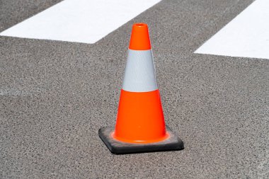 Parlak turuncu trafik konisi asfaltta duruyor.