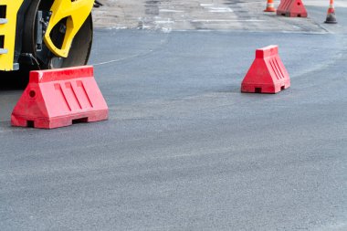 Yeni bir yol inşaatı. Yeni yol inşaatında çalışan bir yol silindiri. Plastik yol eskrimi.