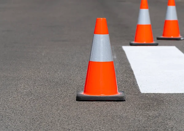 Road traffic cones standing on street on gray asphalt during road construction works. Traffic cones for road works.