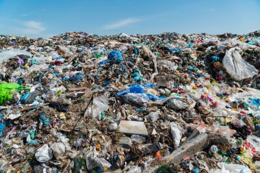 Mavi gökyüzüne karşı çöplükte bir çöp yığını. Çöp sahasında plastik hurda.