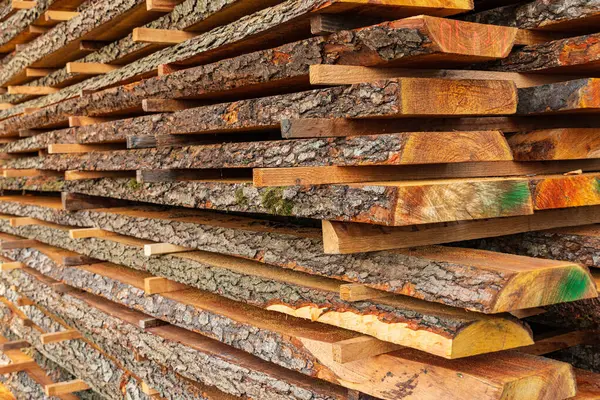 Wooden timber at a sawmill. Boards with bark.