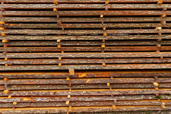 Pine boards on a sawmill. Stacks of boards on a sawmill. Boards with bark.