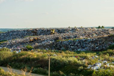 Çevre kirliliği. Çöplükte ya da çöplükte çöp yığını var. İki buldozer bir çöplükte çalışıyor..
