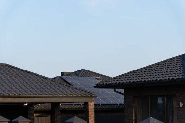 Günümüz evlerinin çatılarına güneş panelleri monte edilir ve güneşli bir günde sakin bir banliyö bölgesinde sürdürülebilir bir enerji seçimi sergilenir..