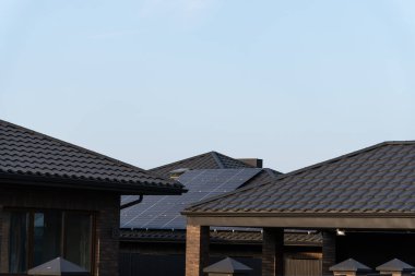 Çağdaş evlerin çatılarında güneş panelleri yer alıyor ve toplumdaki sürdürülebilir enerji eğiliminin giderek arttığını vurguluyor..