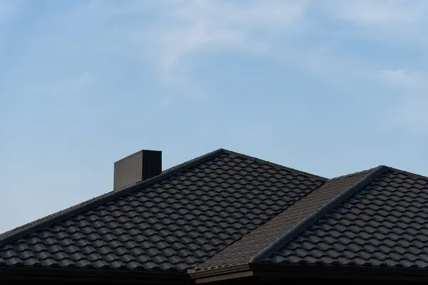 stock image The structure features two gabled roofs with textured tiles, standing prominently under a bright blue sky, highlighting the craftsmanship of the residential architecture.