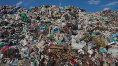Büyük bir atık alanı, atık maddelerin zamanla nasıl biriktiğini gösteren bir dizi dökümlerle doludur. Plastiklerin ve molozların canlı karışımı gökyüzüne karşı belli oluyor.
