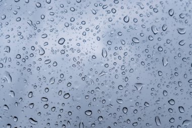 Hassas damlacıklar cam yüzeyde toplanarak gri ve bulutlu bir gökyüzü sergiliyorlar. Atmosfer sakin ve içsel, bir sakinlik hissi uyandırıyor..