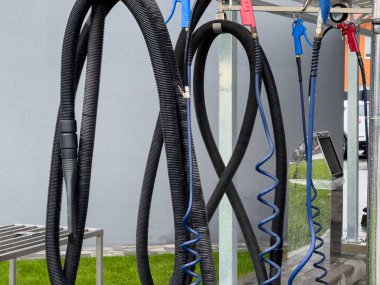 Yüksek basınçlı araba yıkama makineli tüfekleri bir oto yıkamada asılı duruyor. Bu temel araçlar, araçlar için verimli temizlik göstergesi olarak düzenlenmiş ve çalışmaya hazırdır..