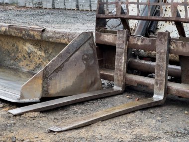 Bir vaşak ve kazıcı, çakıl ve makine arasında toprak taşıma görevlerini yerine getirmeye hazır bir inşaat sahasına yerleştiriliyor..