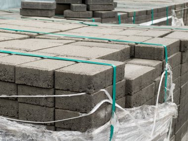 İnşaat alanında kullanılması beklenen çeşitli beton kaldırım blokları plastik ambalajla korunuyor. Bu materyaller kentsel kalkınma projeleri için çok önemlidir.