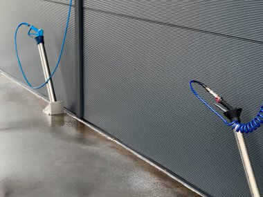 Yağmurlu bir günde araçlarını temizlemeye çalışan kullanıcılar için hazırlanmış iki adet yüksek basınçlı yıkama çubuğu açık bir oto yıkama istasyonuna yerleştirilmiştir..