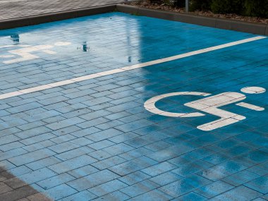 Erişilebilir park yeri için tasarlanmış açık mavi kaldırımda ikonik engellilik sembolü yer alıyor. Sergide, hareket güçlüğü çekenler için kentsel planlamaya kendini adamış durumdalar.