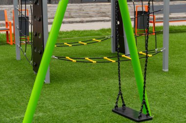 Çocuklar parlak renkli bir salıncakta sallanmaktan hoşlanırlar, yemyeşil çimlerle çevrili, güneşli bir günde oyun ve keşfi davet eden.