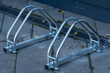 İki şık, modern bisiklet park yeri, güneşli bir kaldırımda, bisikletçileri şehrin tadını çıkarırken bisikletlerini güvene almaları için cesaretlendiriyor..