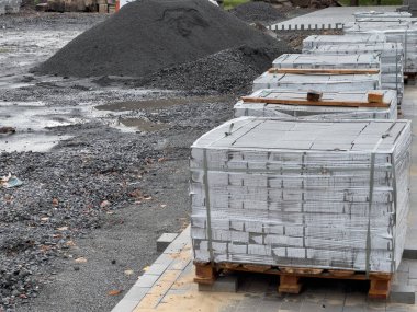 Gri beton bloklarla dolu sandıklar paletlerin üzerine düzgünce yerleştirilmiştir. Günün erken saatlerinde yoğun bir alanda inşaatta kullanılmaya hazırdırlar..
