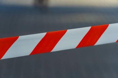 Kırmızı ve beyaz uyarı bantlarının çarpıcı deseni açık bir alana yayılarak, güneşli bir günde çevre ile parlak bir tezat oluştururken kısıtlı erişimin sinyallerini verir..