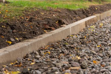 Yeni yapılmış beton kaldırım, çevresindeki yeşilliklere karışan toprak tonlarıyla çakıl yolu çiziyor. Düşen yapraklar, sakin atmosfere sonbahar havası katar..