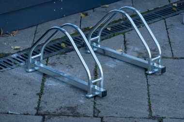 İyi tasarlanmış bisiklet rafları hareketli bir mahallede sürücüler için hazırdır. Metalik yapı güneş ışığı altında parlıyor, bisikletçileri güvenli bir yere park etmeye ve gelişmeye davet ediyor..