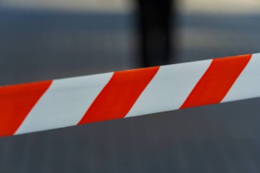 Parlak kırmızı ve beyaz uyarı bantları şehrin kaldırımlarını kaplıyor ve bariyer görevi görüyor. Açık bir gökyüzünün altında göze çarpan canlı renkleri, yoldan geçenleri yasak bir bölgeden uzaklaştırıyor..