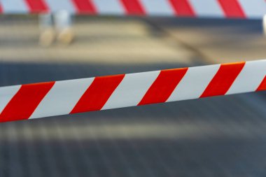 Parlak kırmızı ve beyaz uyarı bantları, belirlenmiş bir bölgedeki tehlike ve kısıtlamaları işaret ediyor. Kaset yayalar ve araçlar için açık bir uyarı niteliği taşıyor..