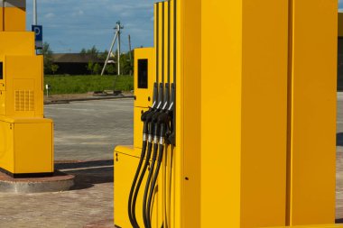 Bright yellow gas dispensers are prominently positioned at a fuel station, offering a convenient refueling option for vehicles on a clear day. The surroundings are open and spacious. clipart