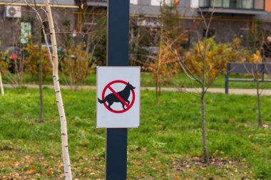 Çimenli bir alana köpek gezdirmenin yasak olduğunu belirten bir uyarı işareti konmuştur. Sembol kırmızı çemberin içindeki bir köpeği gösteriyor, bir kesikle, kuralları güçlendiriyor..
