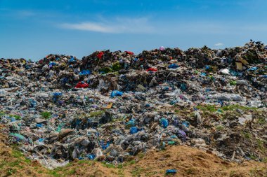 Büyük bir çöp sahası, kirlilik ve atık tasfiye uygulamalarının yol açtığı çevresel sorunları vurgulayarak, plastik, enkaz ve reddetme de dahil olmak üzere çöp katmanlarını ortaya çıkarıyor..