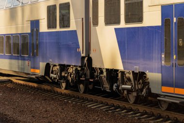 Bir elektrikli tren gün batımında tren rayları boyunca sorunsuzca ilerliyor..