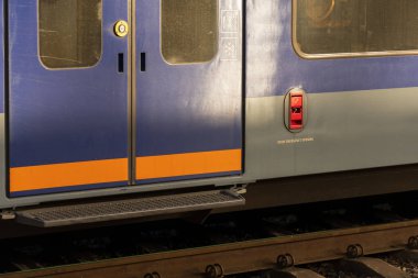 Çarpıcı mavi tren kapıları yoğun bir istasyonda göze çarpıyor. Şık tasarımlarını ve çevrenin heyecanla vızıldadığı banliyö sakinlerini hoş karşılıyor..