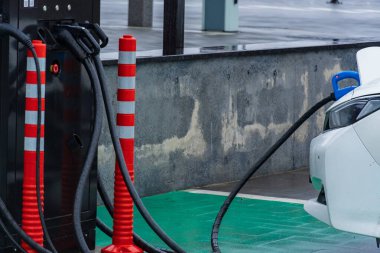 Şık bir elektrikli araç enerji çözümlerindeki modern ilerlemeyi vurgulamak için bir şarj istasyonuna bağlanıyor..