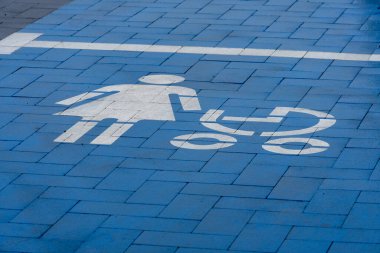 Mavi boyanmış bir park yerinde, bebekleri olan anneler için belirlenmiş park yerini gösteren bir kadın ve bebek arabasının açık bir sembolü vardır. Bu alan erişilebilirliği ve kolaylığı teşvik eder.