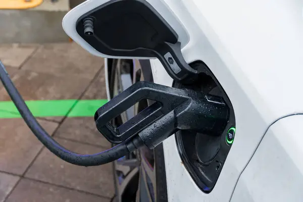 Elektrikli bir araç şık bir şarj istasyonuna bağlanıyor, enerji verimliliği ve çevre dostu ulaşım seçenekleri için gelişmiş teknoloji sergiliyor.