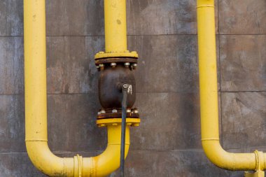 Sarı metal boru ve valfler, enerji taşıma teknolojisini ön plana çıkaran endüstriyel altyapı içinde bir gaz boru hattı bağlantısı gösteriyor.