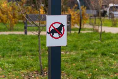 Köpeklere izin verilmediğini belirten bir parktaki uyarı levhası, ziyaretçiler için temiz açık alanların önemini vurguluyor..