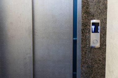 Çelik asansör kontrol paneli bir bina içinde kolay navigasyon için kat numaralarını gösteren aydınlatılmış düğmeleri gösterir.