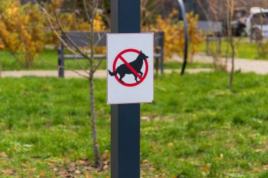 Parkta açık bir uyarı işareti görülebiliyor. Bu da köpeklerin dışkıyı önlemek ve ziyaretçi güvenliğini sağlamak için bu bölgede yasak olduğunu gösteriyor..