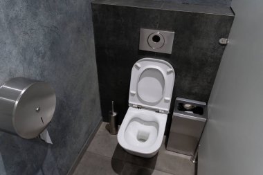 Bu tuvalette modern tesisat tesisatlarına sahip minimalist bir tasarım sergileniyor, bir kamu tesisinde kullanıcılar için temizlik ve rahatlık vurgulanıyor..