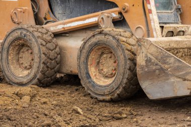 Kazı kazma ve buldozer de dahil olmak üzere ağır makineler güneşli bir günde inşaat alanında toprak kazıyor ve hareket ettiriyor..