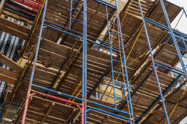 İşçiler, kentsel kalkınma alanındaki endüstriyel ilerlemeyi vurgulayarak, yeni bir binanın inşası için geniş bir yapı iskelesi kuruyorlar.