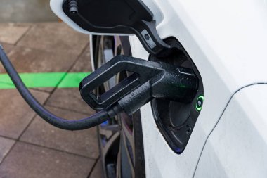 Bir elektrikli araba, sürdürülebilir enerji kullanımı ve ulaşım teknolojisinin geleceğini vurgulayan bir şarj istasyonuna bağlanır..