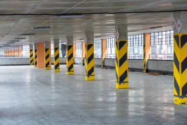 Geniş yeraltı otoparklarında sarı ve siyah sütunlar ve parlak beton zeminler sergilenerek modern bir ortam yaratılıyor..