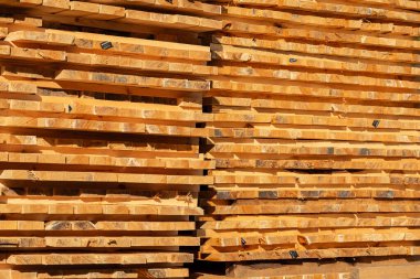 Kereste kütükleri kereste deposunda güzelce istiflenir, zengin renklerini ve pürüzsüz dokularını sergilerler, ahşap işçiliğinin kalitesini ön plana çıkarırlar..