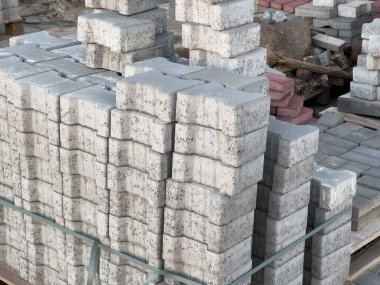 Yoğun bir inşaat sahasında beton bloklar ve desenli taşlar düzgün bir şekilde düzenlenir ve projeler inşa etmeye hazırdır..
