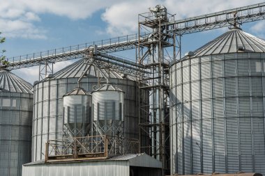 Çelik silolar ve tahıl ambarları temiz bir gökyüzüne karşı yükseliyor, tarım ve tarım operasyonlarında verimli tahıl depolamanın önemini simgeliyor..