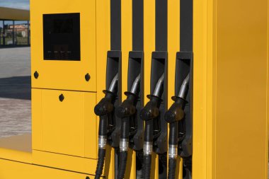 Bir benzin istasyonunun benzin deposunda, müşterilerin araçlarını benzinle doldurmaya hazır dört yakıt hortumu görülüyor..